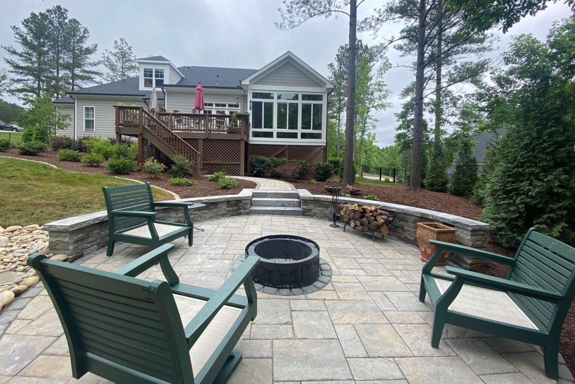 Photo of a backyard firepit surrounded by lush lawn and gardens